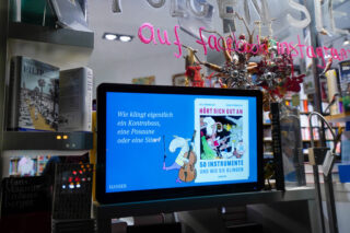 Bildschirm mit Buchempfehlung in einem Schaufenster