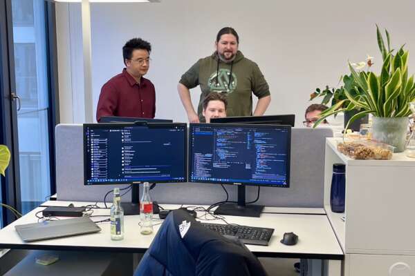 EIn Team steht zusammen um einen Computer