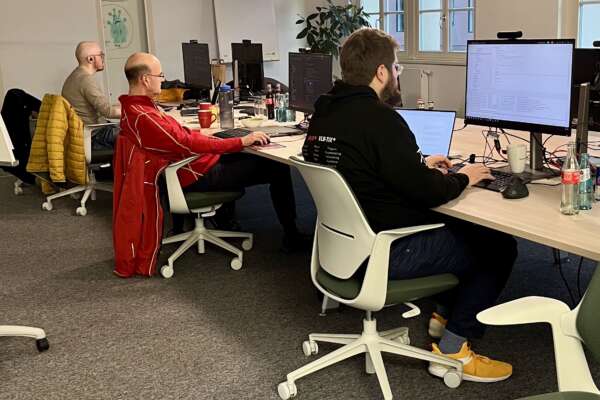 Drei Teilnehmende sitzen nebeneinander vor ihren Computern