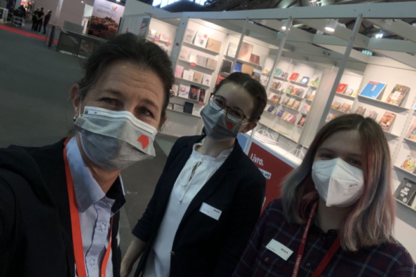 Selfie of Katharina Oppitz, Anna Göckel and another woman in front of a stand at the Frankfurt Book Fair.