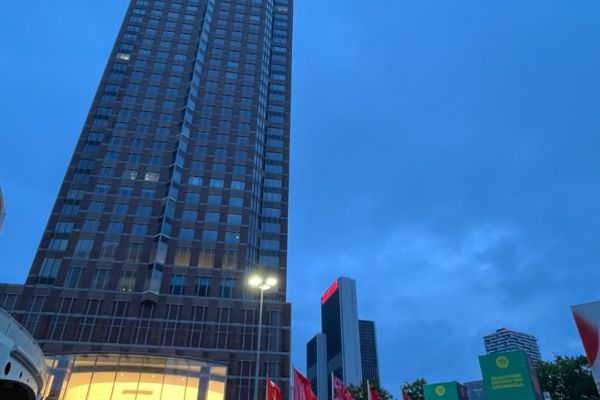 The Tower of Frankfurt Fair with an illuminated entrance hall which rises up in the blue night sky.